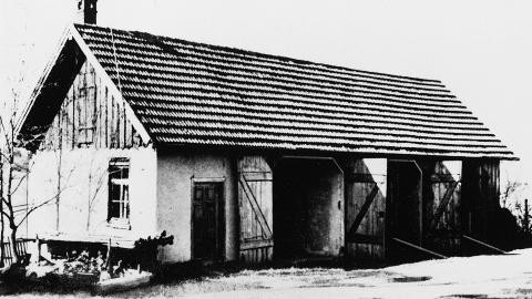 Zur Landwirtschaft gehörendes Gebäude ("Remise"), in das zur Jahreswende 1939/40 eine Gaskammer eingebaut wurde. Das Bild zeigt ein längliches, weißes Gebäude. Links am Gebäude befindet sich eine Tür, rechts daneben drei Tore aus Holz. Die beiden mittleren Tore sind geöffnet.